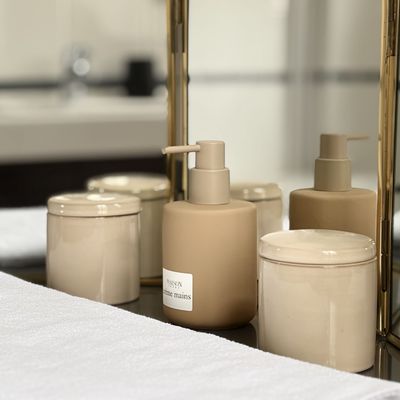Flacons de crème mains et savon devant un miroir triptyque doré