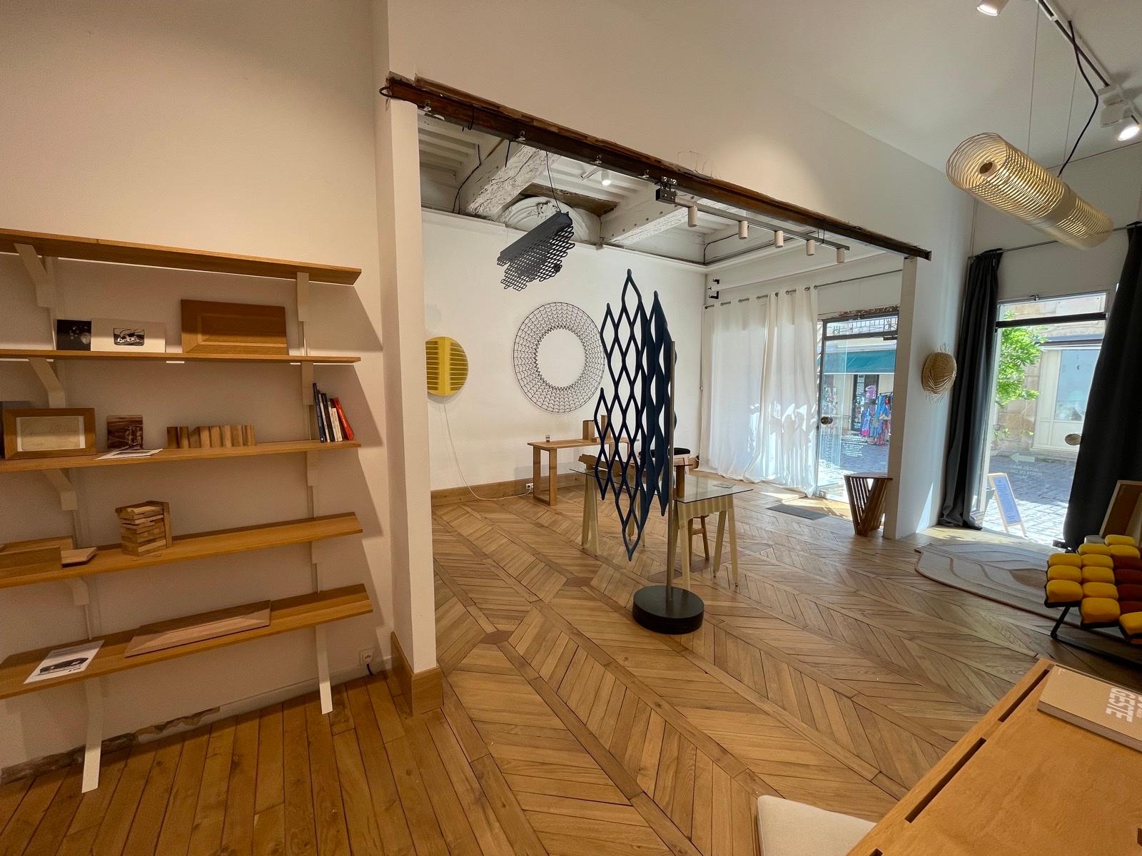 Intérieur de l'Atelier Variation à Semur-en-Auxois — pièces uniques, créations textiles et objets en bois exposés sous une charpente ancienne