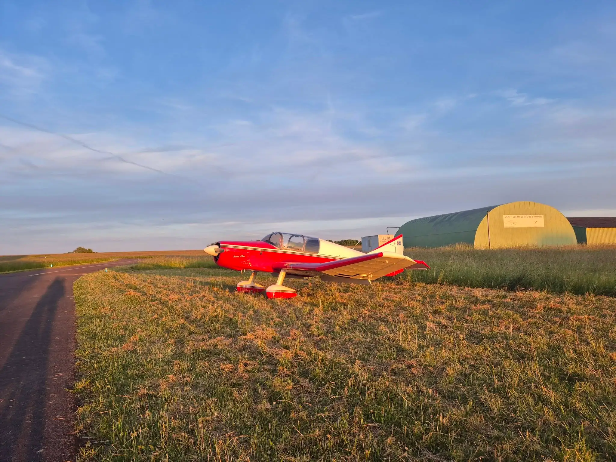Avion de tourisme posé sur l'aérodrome de Semur-en-Auxois (LFGQ) au coucher du soleil, devant un hangar