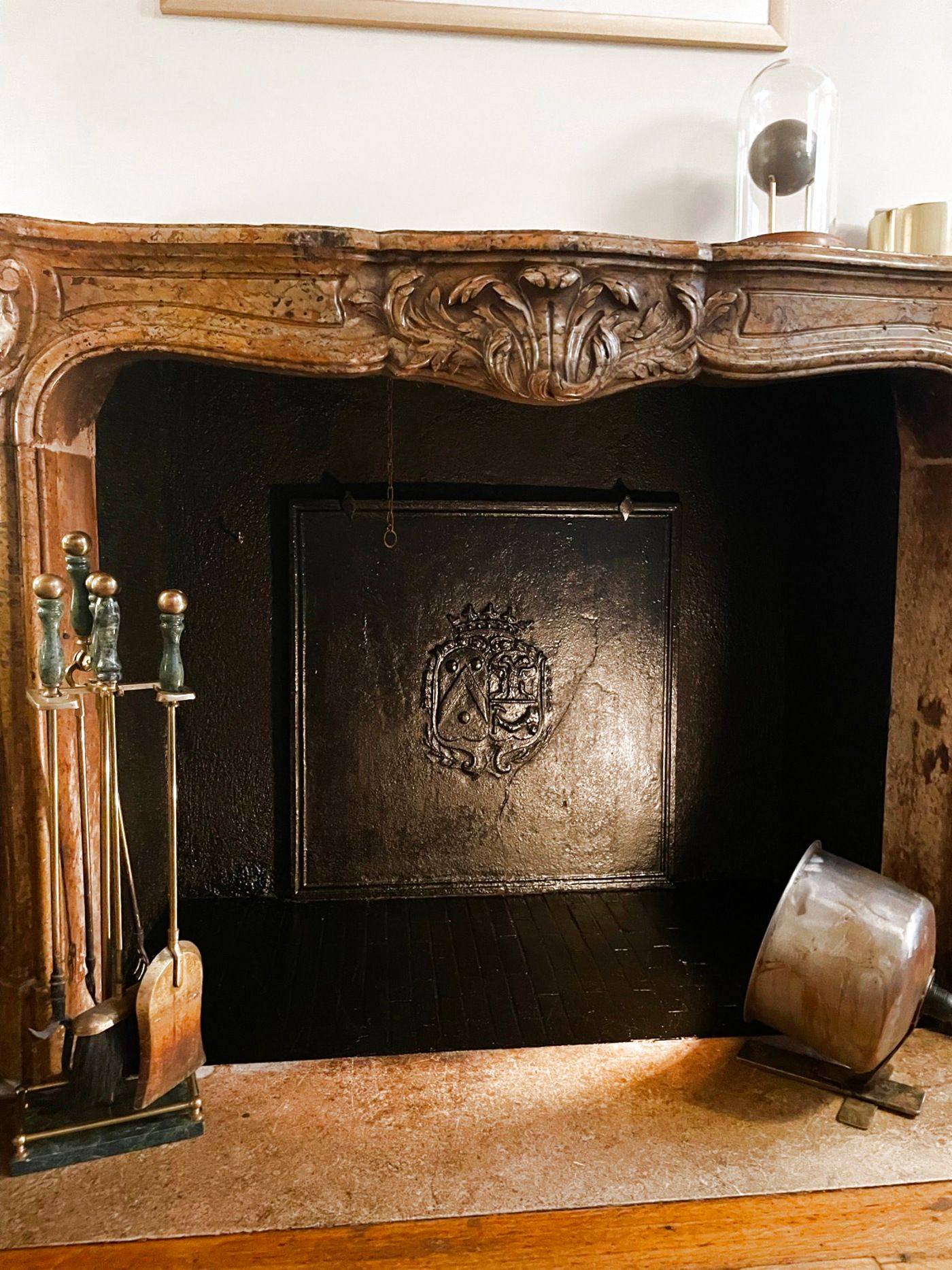 Taque de cheminée en fonte ornée d'un blason en relief, sous un manteau de pierre sculptée