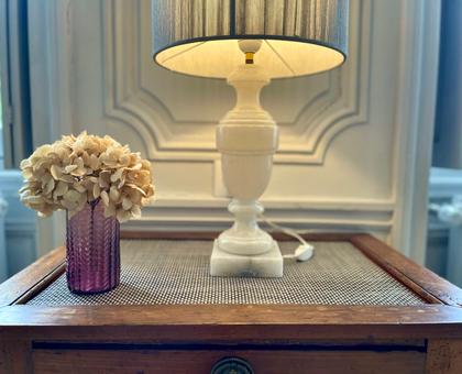 Lampe allumée et bouquet d'hortensias séchés sur une table en bois devant des boiseries blanches