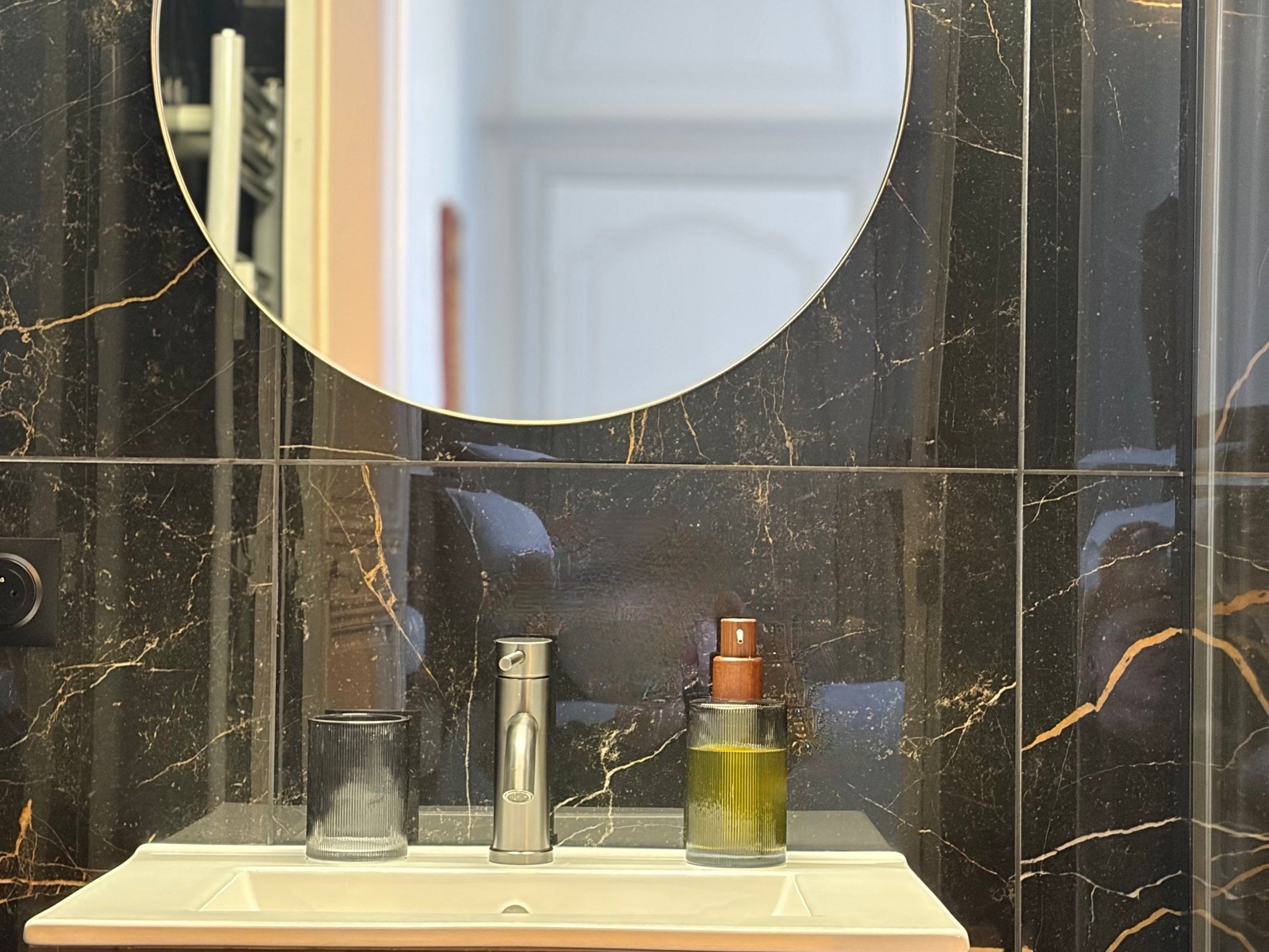 Produits de soin et verre strié sur la vasque de la salle de bain en marbre noir du Studio Côté Cour