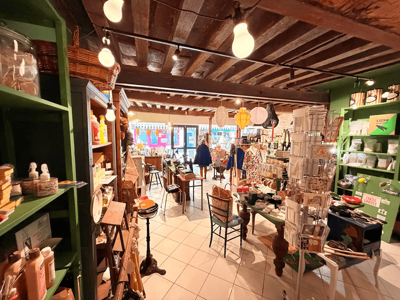 Intérieur de La Droguerie Buffon à Semur-en-Auxois — concept store et lieu d'exposition, hautes étagères vertes et poutres anciennes
