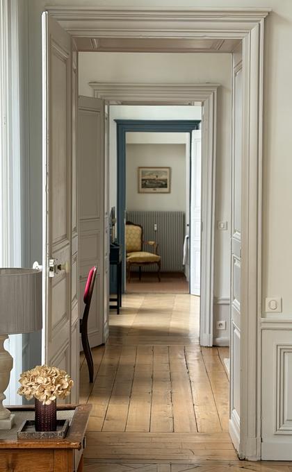 Enfilade de pièces avec boiseries blanches, parquet de chêne et lumière naturelle