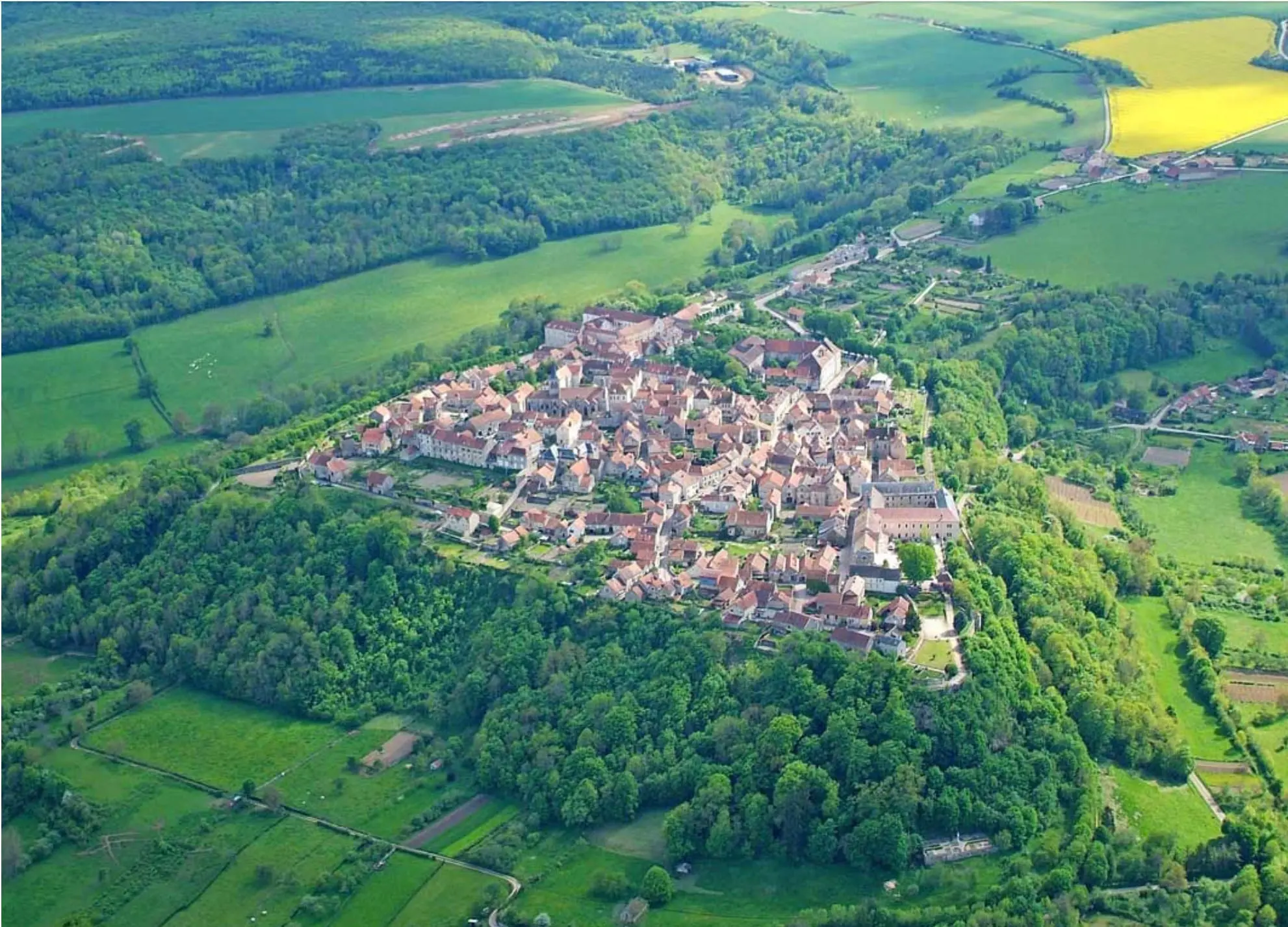 Vue aérienne de Flavigny-sur-Ozerain perché sur son éperon rocheux, entouré de champs et de forêts de l'Auxois