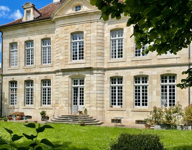 Jardin privé clos de murs avec verdure et façade en pierre