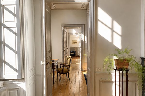 Perspective en enfilade de la Suite Côté Jardin : portes alignées, parquet en chevrons et lumière traversante