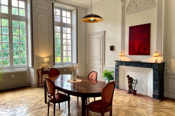 Salle à manger aux volumes d'hôtel particulier : parquet de Versailles, cheminée en marbre et hautes fenêtres sur le jardin