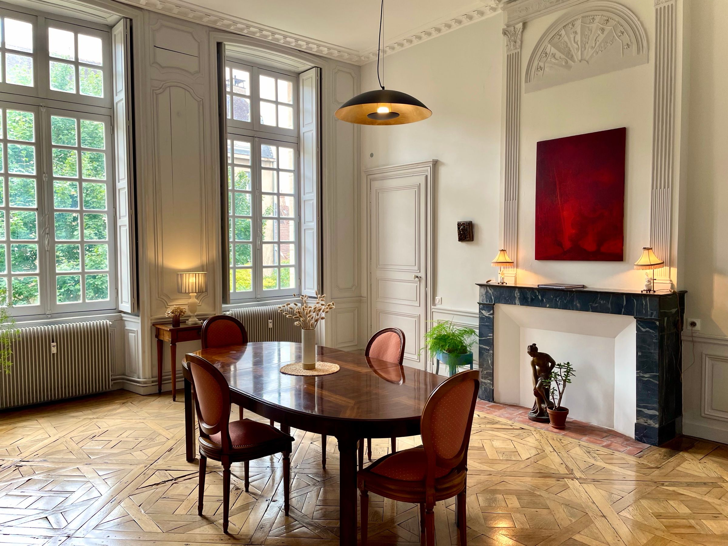 Salle à manger de la Suite Côté Jardin : parquet de Versailles, cheminée en marbre, hautes fenêtres sur le jardin et boiseries du XVIIIᵉ siècle